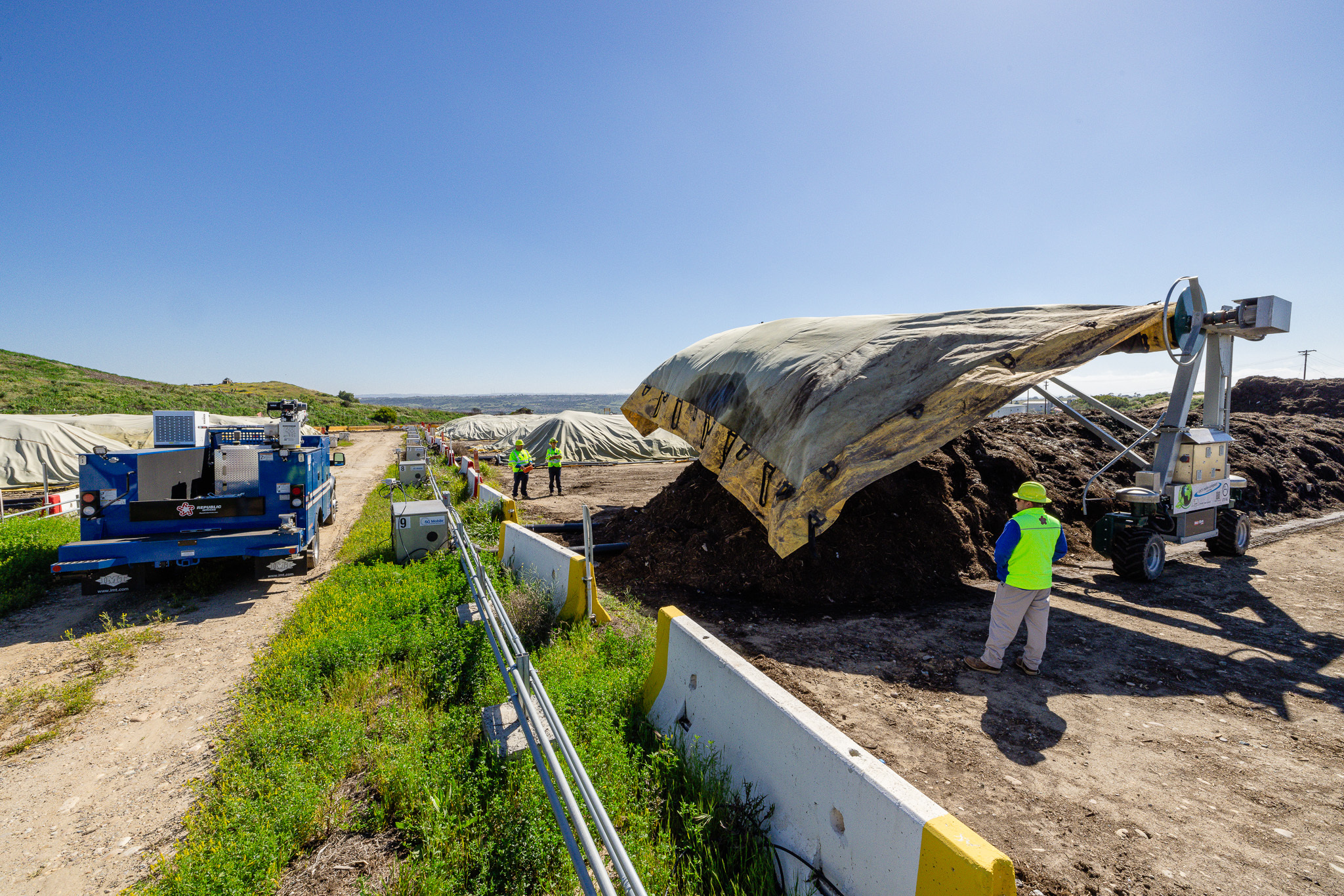 The compost team unwraps a GORTEX™ cover over the material to start phase 1 of the compost process.